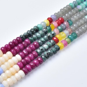 May include: Multiple strands of faceted round beads arranged in parallel rows. The beads feature a diverse color palette including cream, light blue, magenta, dark green, yellow, red, pink, and translucent gray, creating a vibrant display.