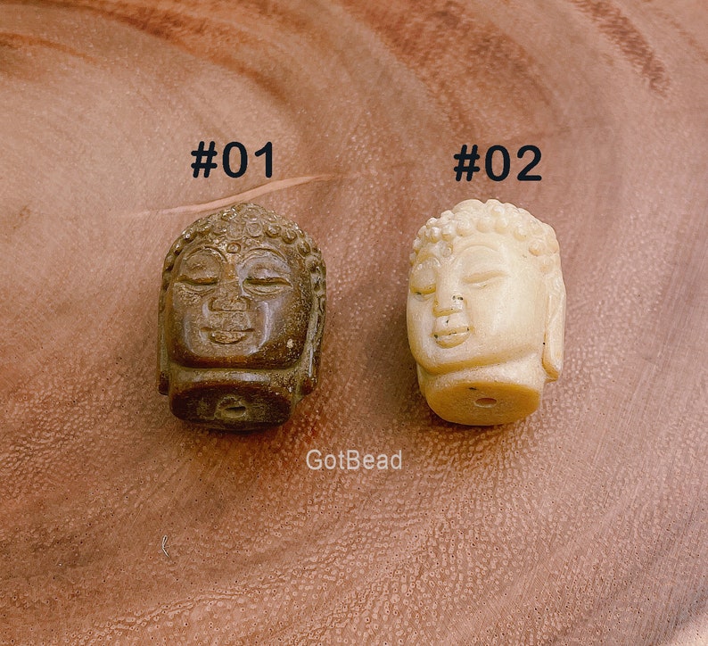 以下が含まれることがあります： 2つの小さな石製の仏陀の頭部のビーズ。1つは茶色で、もう1つは白。上に#01と#02のラベルが貼られています。