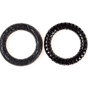 May include: Two black rings are displayed against a white background. The ring on the left is covered in small, sparkling black stones. The ring on the right has a geometric, textured design.