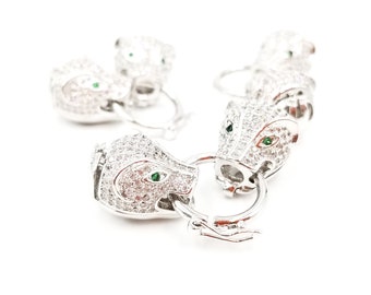 May include: A silver charm bracelet with multiple panther head charms. Each charm is adorned with clear and green cubic zirconia stones.