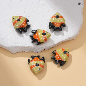 May include: Five small, decorative fish figurines. Each fish has a yellow body with orange stripes and black fins. The figurines are arranged on a white, textured surface. The number "#01" is in the upper right corner.
