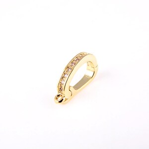 May include: Gold-toned metal clasp with a row of clear rhinestones. The clasp is designed to be used as a connector for jewelry.
