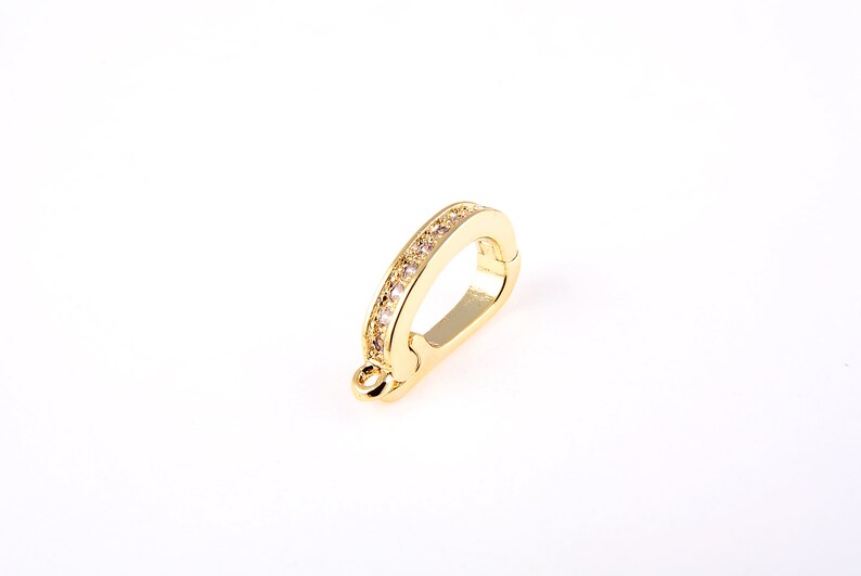 May include: Gold-toned metal clasp with a row of clear rhinestones. The clasp is designed to be used as a connector for jewelry.