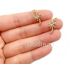 May include: Two gold palm tree charms with colorful crystal accents. The charms are small and delicate, perfect for adding a touch of tropical flair to jewelry.