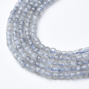 May include: Strands of faceted, light gray beads with subtle blue flashes. The beads are small, cube-shaped, and strung together, creating a delicate and shimmering effect. Ideal for jewelry making, these beads offer a neutral color palette with a touch of iridescence.