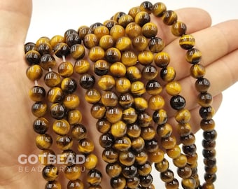 May include: A strand of round, golden brown tiger's eye beads. The beads have a natural, polished finish and a slight sheen. The beads are strung on a clear elastic cord.