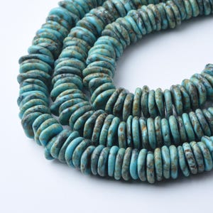 May include: Strands of turquoise-colored, disc-shaped beads. The beads have a mottled appearance with shades of blue and brown. The beads are strung together, forming a necklace or bracelet.