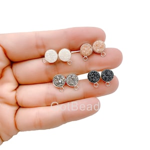 Puede incluir: Conjunto de seis hallazgos de pendientes redondos, planos y plateados con un bucle en la parte posterior. Los hallazgos están coronados con una piedra redonda, plana y brillante en blanco, negro y dos tonos de rosa.