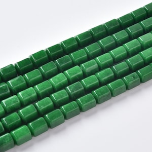 May include: A strand of smooth, square-shaped beads in a vibrant emerald green color. The beads are arranged in multiple parallel rows, showcasing a uniform, polished finish and a consistent cubic geometry throughout the entire length of the strand.