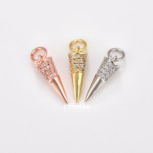 May include: Three cone-shaped charms with a clear crystal design. The charms are gold, silver, and rose gold.