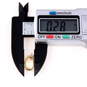May include: A silver digital caliper measuring a gold-colored metal object. The caliper display reads "0.28 in".