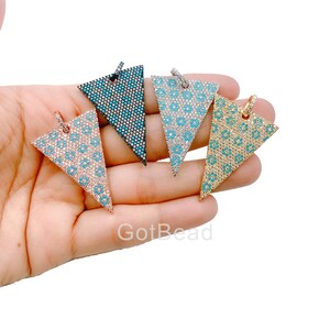 Puede incluir: Cuatro colgantes en forma de triángulo con un diseño micropavé turquesa y blanco. Los colgantes son en negro, plata, oro y oro rosa.