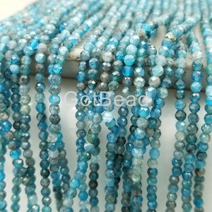 May include: A strand of blue apatite beads, faceted and round, with a slight variation in color from light to dark blue. The beads are strung on a clear thread and are approximately 2mm in diameter.