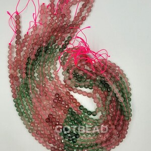 Peut inclure: Un brin de perles facett&eacute;es de couleur verte et rose. Les perles mesurent environ 6 mm de diam&egrave;tre et sont enfil&eacute;es sur un cordon &eacute;lastique rose.