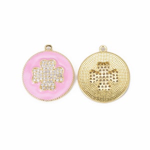May include: Gold-tone pendant with a pink enamel background and a clear rhinestone clover design. The back of the pendant features a gold-tone clover design.