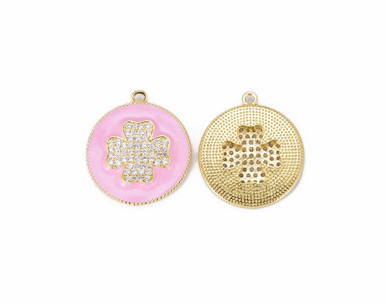 May include: Gold-tone pendant with a pink enamel background and a clear rhinestone clover design. The back of the pendant features a gold-tone clover design.