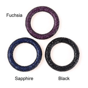 May include: Three circular rings, each encrusted with small, sparkling stones. The rings are in fuchsia, sapphire blue, and black. Text labels identify each color. The rings are set against a white background.
