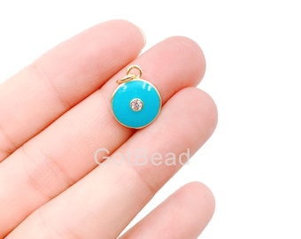Puede incluir: Encanto de oro con un círculo de esmalte azul turquesa y un strass transparente en el centro.