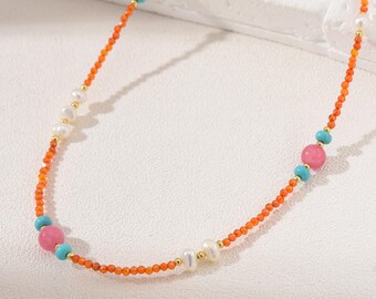 May include: A colorful necklace featuring orange beads, interspersed with pink, turquoise, and red gemstones, and white pearls. The necklace has gold accents and is a delicate piece of jewelry.