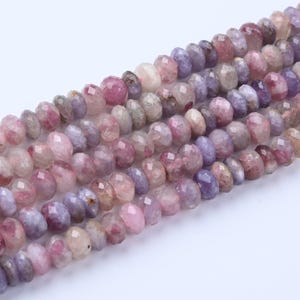 May include: Strands of faceted gemstone beads in shades of pink, purple, and cream. The beads have a polished, irregular shape and are strung together, creating a textured and colorful display. Ideal for jewelry making.
