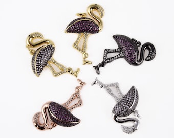 May include: Five flamingo-shaped jewelry charms in various metal finishes including gold, rose gold, silver, and black. Each charm features a body encrusted with small, sparkling pink or clear stones, with a small loop at the top for attachment.