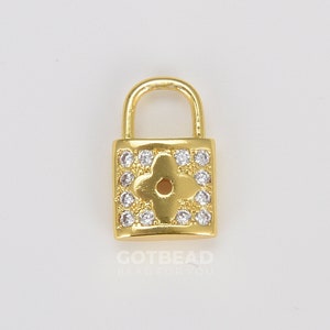 May include: Gold padlock charm featuring a clear crystal flower design. The padlock has a small loop at the top for attaching to jewellery or other crafts.