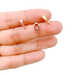 Op de afbeelding: Drie hangerbedels met heldere zirkonia-stenen. De bedels zijn in goud, zilver en rosé goud.