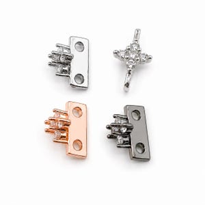 May include: Four metal jewelry connectors in silver, rose gold, and gunmetal tones. Three pieces feature a rectangular base with two holes and a cluster of clear crystals. One piece is a cross-shaped connector with a central cluster of clear crystals.