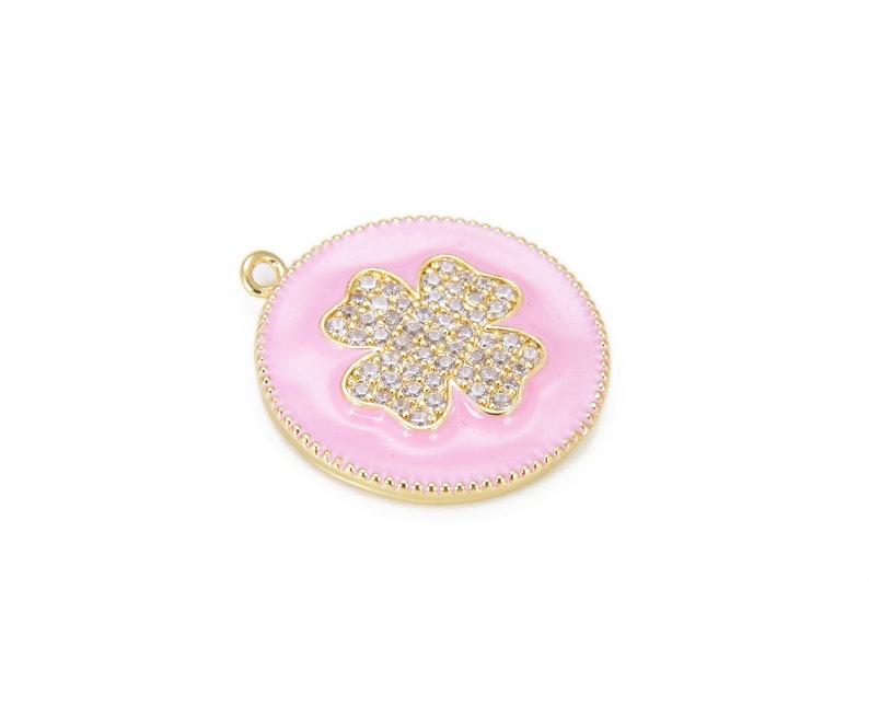 May include: A gold-tone pendant with a pink enamel background and a four-leaf clover design set with clear rhinestones.