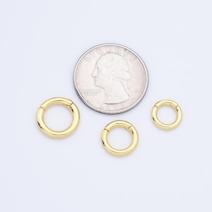 May include: Three gold-coloured hoop earrings of different sizes, shown next to a US quarter for scale.