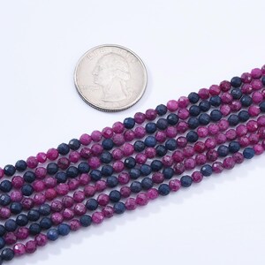 May include: A strand of faceted gemstone beads in shades of pink and blue. The beads are round and have a slightly irregular shape.
