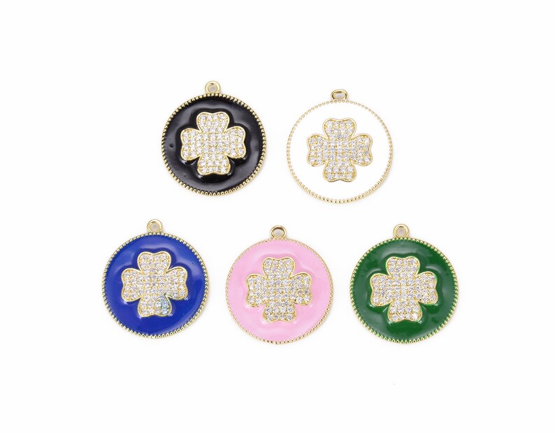 May include: Five gold-tone charms with a four-leaf clover design. Each charm has a different colored enamel background: black, white, blue, pink, and green.