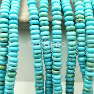 May include: A strand of turquoise beads, each bead is a light blue color with brown and white marbling. The beads are round and have a slightly elongated shape.