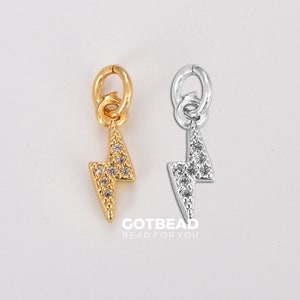 May include: Two lightning bolt charms with clear rhinestones. The charms are gold and silver in color. The charms have a loop at the top for attaching to a bracelet or necklace.