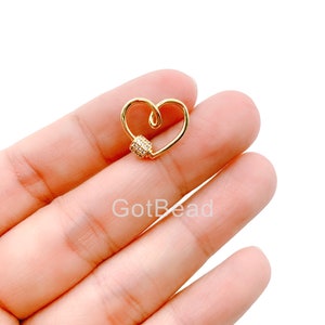 May include: Gold heart-shaped charm with a clear crystal-encrusted bead. The charm is a connector for jewelry making.