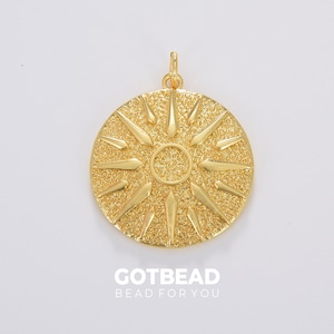 May include: Gold-toned pendant charm with a sun design. The sun has a textured surface and radiating points.