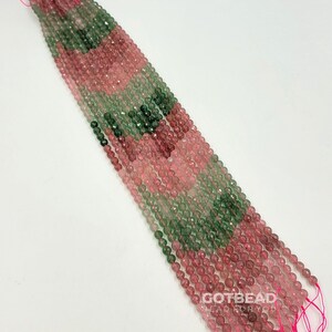 Peut inclure: Un brin de perles facett&eacute;es de couleur rose et verte. Les perles sont enfil&eacute;es sur un fil rose et sont pr&ecirc;tes &agrave; &ecirc;tre utilis&eacute;es pour la fabrication de bijoux.