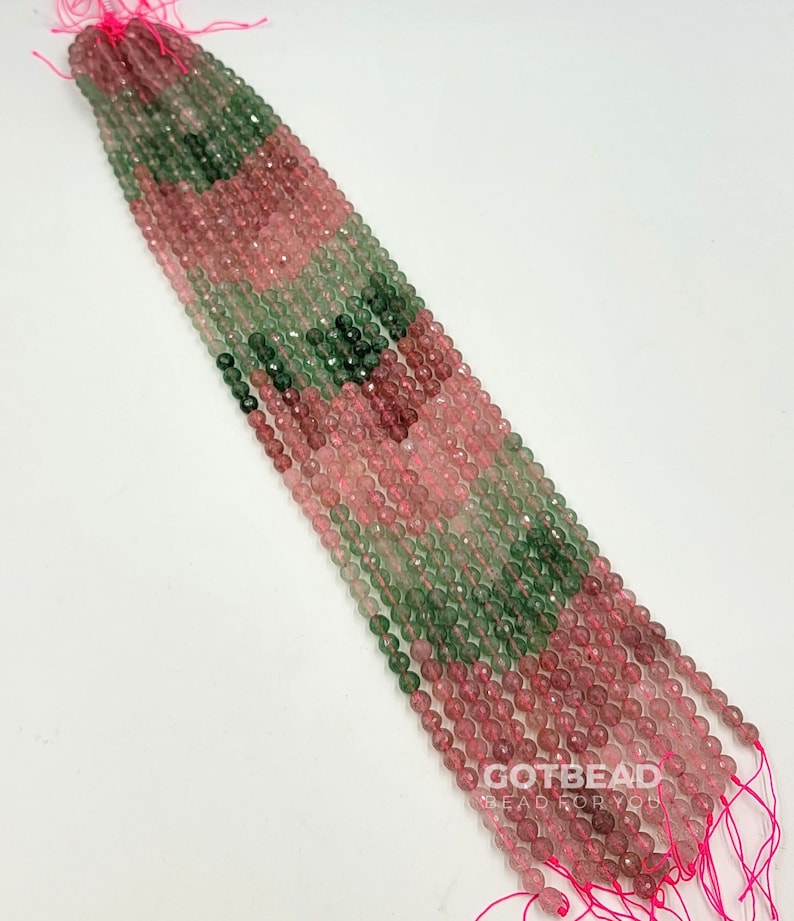 Peut inclure: Un brin de perles facett&eacute;es de couleur rose et verte. Les perles sont enfil&eacute;es sur un fil rose et sont pr&ecirc;tes &agrave; &ecirc;tre utilis&eacute;es pour la fabrication de bijoux.