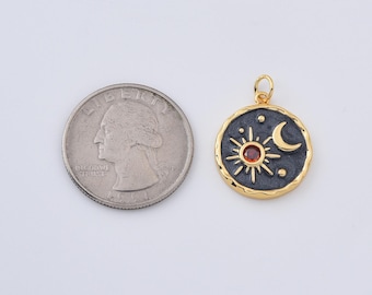 May include: A gold-toned pendant with a sun, moon, and star design, featuring a red gemstone center. The pendant has a dark gray background and a textured gold border. A U.S. quarter is next to the pendant for size comparison.