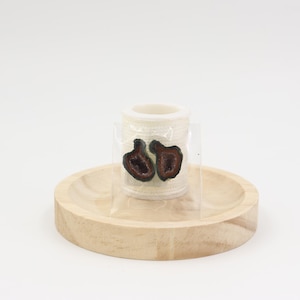 May include: Two dark brown geode-shaped earrings are displayed in a clear plastic bag, set on a small, light-colored wooden tray. The earrings are a deep brown color with a lighter interior. The tray sits on a white surface.