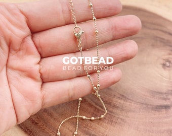 May include: A gold chain necklace with small round beads. The chain is delicate and has a lobster clasp closure. The necklace is approximately 18 inches long.