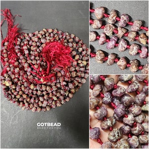 May include: A strand of red ruby gemstone beads with a red tassel on each end. The beads are knotted with red thread. The image includes the text "GOTBEAD BEAD FOR YOU".