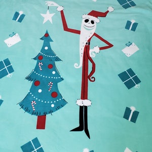 May include: A turquoise blue fleece blanket featuring a Christmas tree and a character dressed as Santa Claus. The character is Jack Skellington from the film The Nightmare Before Christmas. The blanket has a fringed border and is decorated with presents.