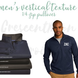May include: A navy blue 1/4-zip pullover with a textured fabric. The pullover has a white zipper and a white embroidered name "ZAC" on the chest. The pullover is shown on a model wearing khaki pants.
