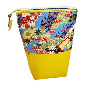 May include: A yellow fabric pouch with a zipper closure. The pouch has a colorful floral pattern with blue, red, green, and gold accents.