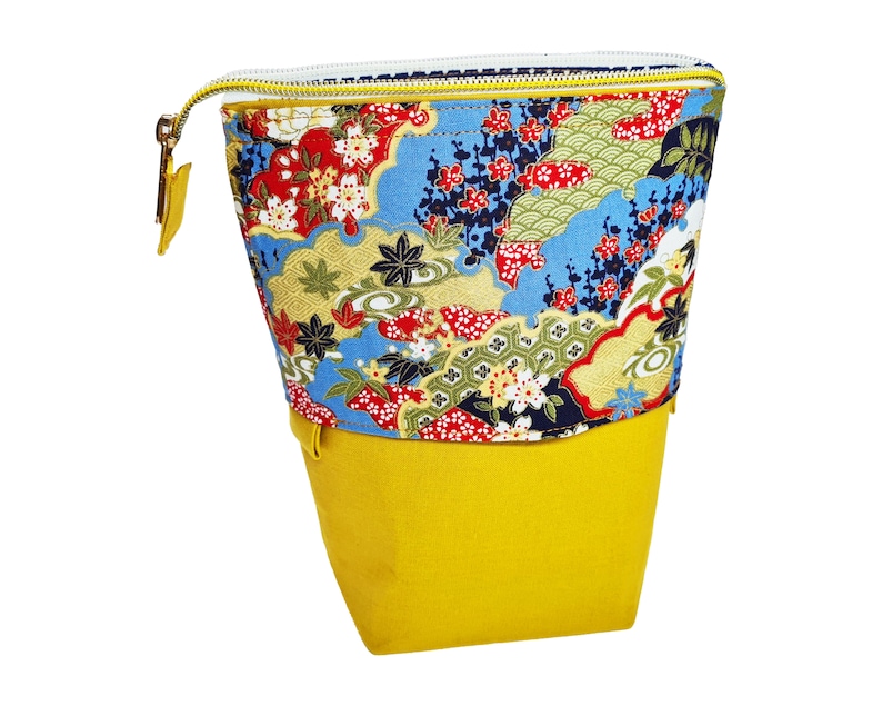 May include: A yellow fabric pouch with a zipper closure. The pouch has a colorful floral pattern with blue, red, green, and gold accents.