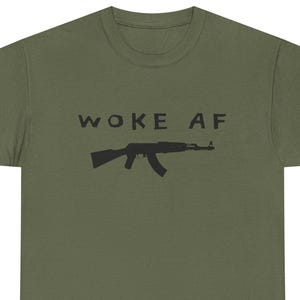 May include: A green t-shirt with the text "WOKE AF" and a silhouette of an assault rifle printed on it.