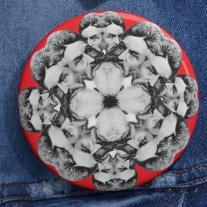 May include: A red button with a black and white kaleidoscope design featuring a man's face repeated in a circular pattern.