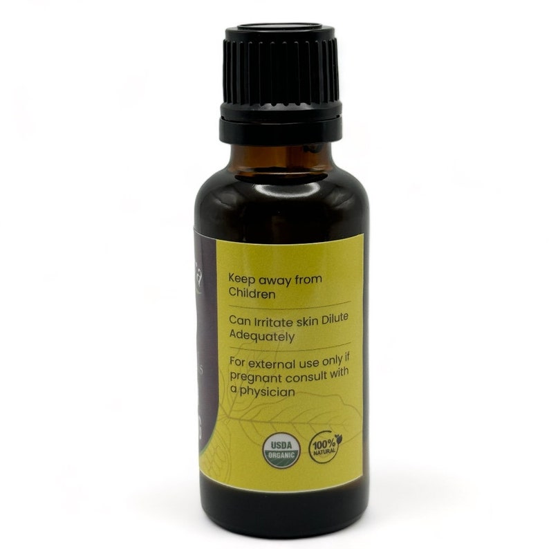 Peut inclure: Une bouteille en verre brun avec un bouchon noir, contenant de l'huile essentielle. L'&eacute;tiquette est jaune avec du texte noir qui indique "Tenir hors de port&eacute;e des enfants", "Peut irriter la peau Diluer ad&eacute;quatement", "Pour usage externe uniquement si enceinte consulter un m&eacute;decin", "USDA Organic", et "100% Naturel".