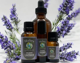 May include: An assortment of essential oil bottles and a roller bottle, with a backdrop of lavender sprigs. The bottles are amber-colored glass with black caps and labels that read "Skylara essentials Bulgarian Lavender."